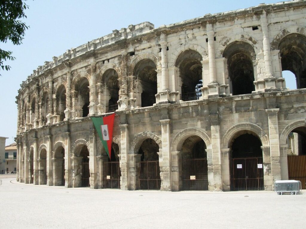 Façade à arcades des arènes romaines de Nîmes sous un ciel clair
