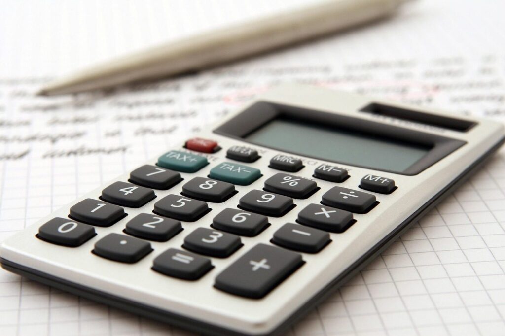 Calculatrice et stylo posés sur une feuille de notes quadrillée