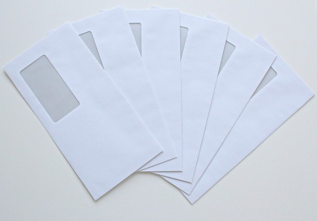 Enveloppes blanches à fenêtre disposées en éventail sur une table