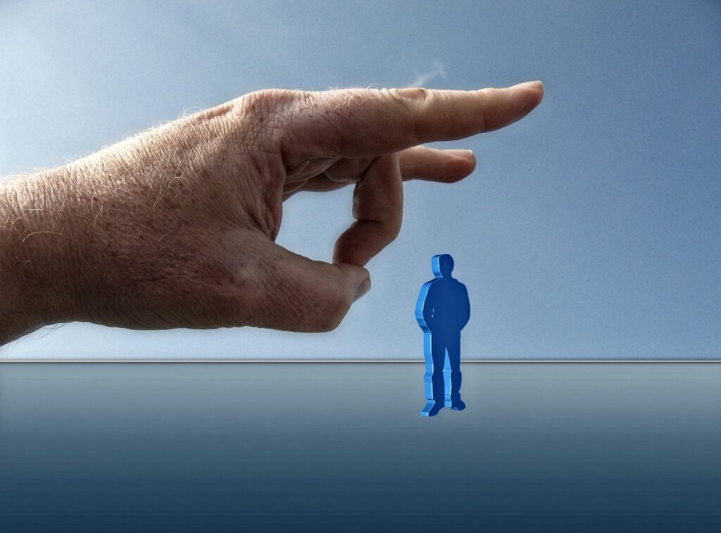 Doigt prêt à chasser une petite figurine humaine, symbole du licenciement